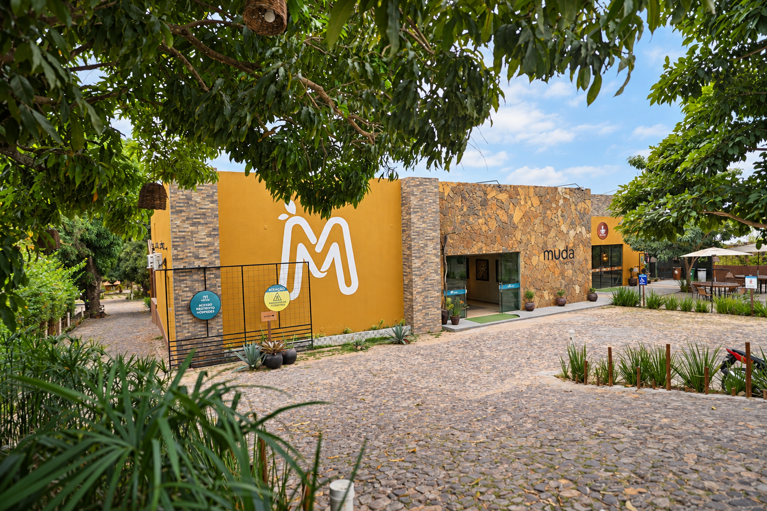 Fachada do Muda Hotel cercada por jardins e árvores